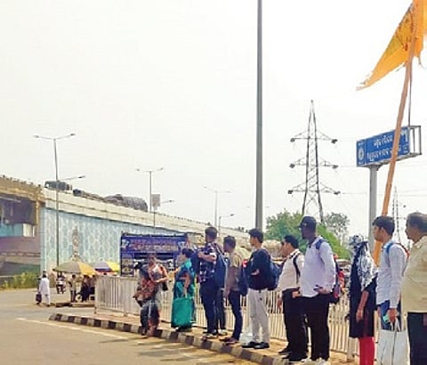 People waiting on the narrow median near Jagatpur Golei square.