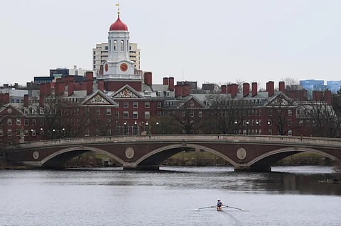 A sculler rows down the Charles River near Harvard University, at rear, Tuesday, April 15, 2025, in Cambridge, Mass.