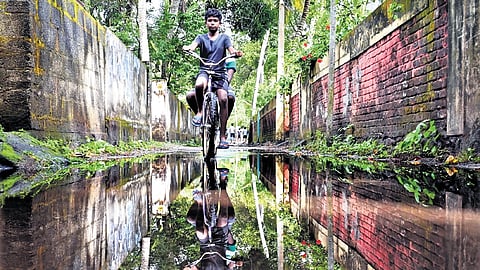 A boy cautiously rides his bicycle through the streets that were inundated in the early morning rain at Vazhamuttom