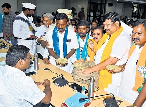 BJP leaders along with farmers display damaged paddy at the Prajavani programme at the integrated district offices complex in Nizamabad on Monday