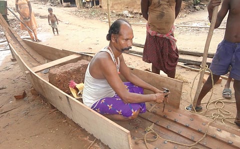 A boat maker working on a wooden boat in Batighar village