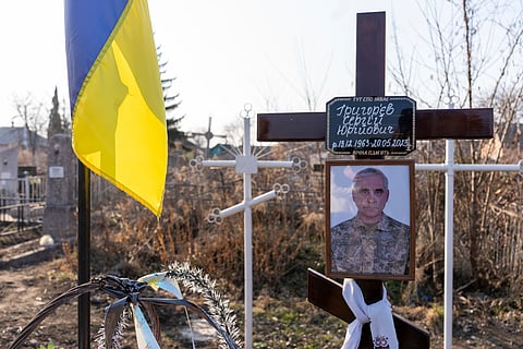 A portrait of Serhii Hryhoriev, a Ukrainian prisoner of war who died in Russia, is seen next to his grave in Pyriatyn, Ukraine.