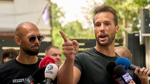 Andrew Tate, left, watches his brother Tristan speak outside a police station in Voluntari, Romania, Wednesday, May 21, 2025.