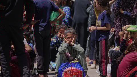 A Palestinian girl waits to collect donated food at a food distribution kitchen in Deir al-Balah, Gaza Strip, Friday, May 30, 2025.