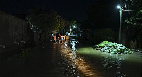 People wade through a road submerged due to rising water level of Howrah river following rains, in Agartala, Friday, May 30, 2025.