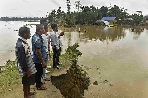 People stand near an embankment washed away at a flood-affected area, in Lakhimpur district, Assam, Sunday, June 1, 2025.