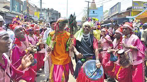 Folk artists playing percussion instruments and dancing.