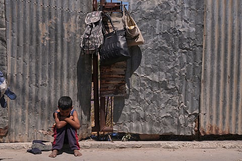 A Palestinian boy sits on the curb as he waits near a food distribution kitchen in Deir al-Balah, Gaza Strip, Friday, May 30, 2025.