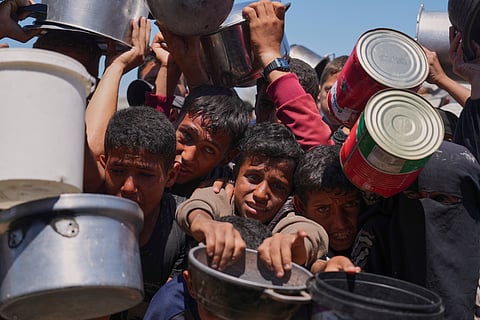 Palestinians struggle to get donated food at a community kitchen in Khan Younis, southern Gaza Strip, Monday, June 2, 2025.