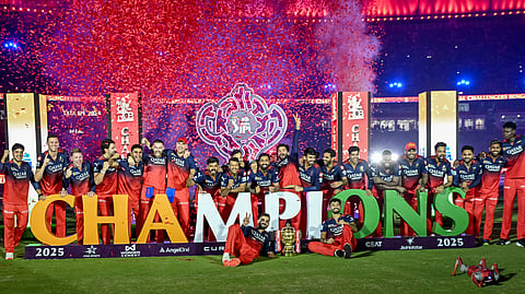 Royal Challengers Bengaluru's players pose for photographs with the trophy after winning the Indian Premier League (IPL) Twenty20 final cricket match against Punjab Kings at the Narendra Modi Stadium in Ahmedabad on June 4, 2025.