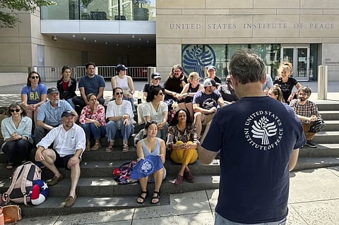 U.S. Institute of Peace employees hold an impromptu celebration on the steps of the U.S. Institute of Peace, Monday, May 19, 2025, in Washington, after federal district Judge Beryl A. Howell blocked the Trump administration from moving forward with dismantling the organization.