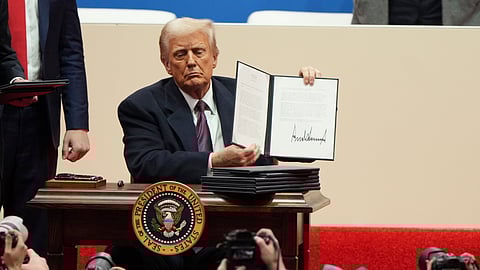 President Donald Trump holds up an executive order after signing it at an indoor Presidential Inauguration parade event in Washington.