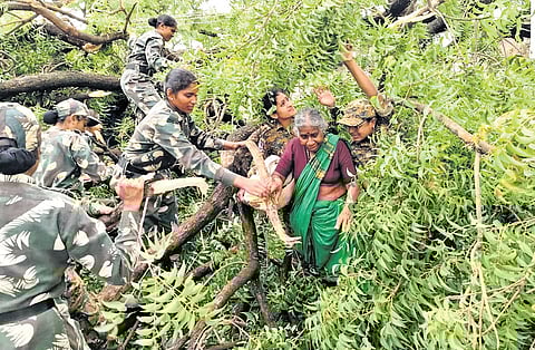 Team Shivangi, an all-women commando unit of Nirmal police, helps an elderly woman come out safely after trees fell on the road in Nirmal district on Tuesday