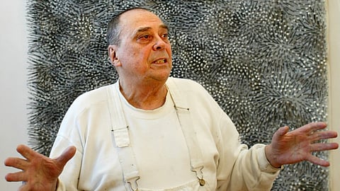 In this Wednesday, March 9, 2005 file picture German artist Günther Uecker, one of the country's most important post-war artists who was famous for his large-format nail reliefs, stands in front of his artwork 'Feld' (Field) in Berlin.