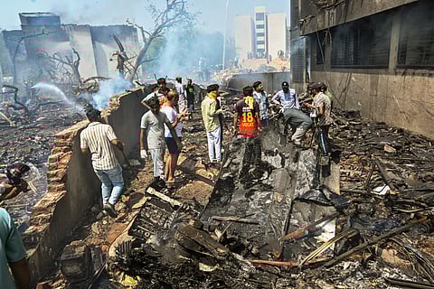 People stand near the debris of the Air India plane that crashed moments after taking off from the airport, in Ahmedabad, Thursday, June 12, 2025.