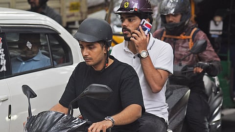 Motorist and pillion rider riding with a half-helmet in Bengaluru.
