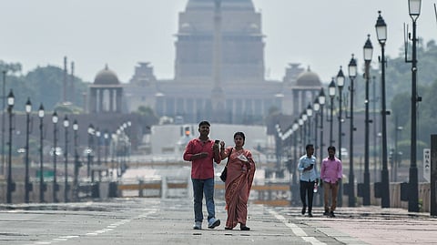 People walk under the scorching sun at the Kartavya Path area in New Delhi.