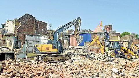 Bulldozers demolish illegal structures during an anti-encroachment drive conducted by DDA in the Govindpuri area on Wednesday.