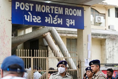 Security personnel stand near the post-mortem room of a hospital where victims of yesterday's Air India plane crash were admitted, in Ahmedabad, Friday, June 13, 2025.
