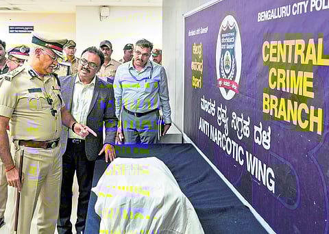 Bengaluru City Police Commissioner Seemant Kumar Singh examines seized narcotics during a press conference, in Bengaluru on Friday