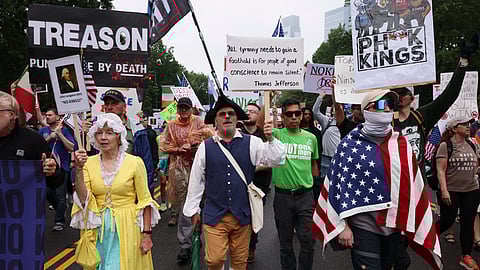 Demonstrators dressed in Revolutionary War era clothing march down Benjamin Franklin Parkway during the "No Kings" protest, Saturday, June 14, 2025, in Philadelphia