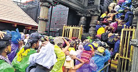 Devotees wearing raincoats throng the Sabarimala temple on Sunday