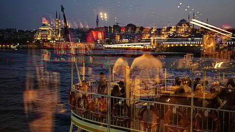 Passengers, seen through a window, get on board a ferry ship before departing from Karakoy ferry terminal, in Istanbul, Turkey, Friday, June 13, 2025.