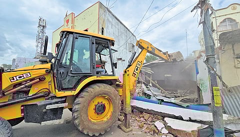 An earthmover demolishes buildings as road-widening works begin in Vemulawada, Rajanna-Sircilla district, on Sunday.