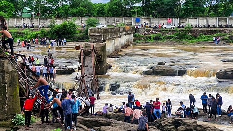 People stand near an iron bridge over the Indrayani river after it collapsed, in Pune district, Maharashtra, Sunday, June 15, 2025. Some people are feared to have been swept away after the collapse.