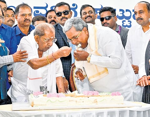 Former minister Dr Shamanur Shivashankarappa feeds a piece of cake to CM Siddaramaiah on his 95th birthday, in Davanagere on Monday