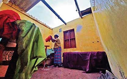 Susi John, a resident of Karuppai Road near Valiyathura in Thiruvananthapuram, scrambles to protect her belongings after heavy rain and strong winds blow off the roof of her second-floor home.