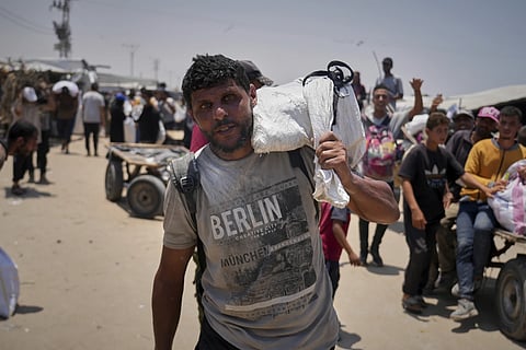 Omar al-Hobi, 43, from Rafah, carries a bag of food he collected at a distribution center run by private contractor The Gaza Humanitarian Foundation in the southern Gaza Strip, as he arrives at his tent in Khan Younis, Tuesday, June 10, 2025.