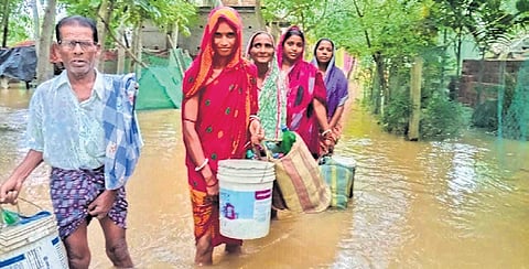 People wade through knee-deep floodwater at Kumbhirgadi village in Balasore distict.
