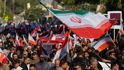 Protesters carry Iranian flags during a rally to show solidarity with Iran, in the Shi'ite district of Kazimiyah, in Baghdad, Iraq, Saturday, June 21, 2025