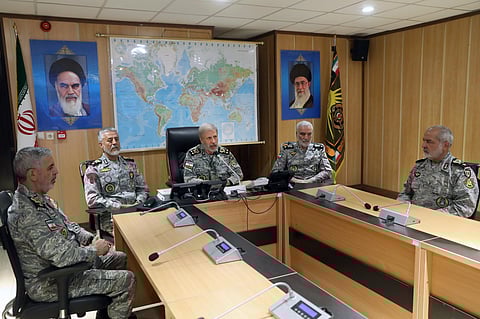 In this photo released on Monday, 23, 2025, by Iranian army press service, Iran's army commander-in-chief Gen. Amir Hatami, center, accompanied by high ranked army commanders, speaks in a video call with top commanders of the army, in Zolfaghar central headquarters, Iran, as portraits of the late revolutionary founder Ayatollah Khomeini, left, and Supreme Leader Ayatollah Ali Khamenei hang on the wall.