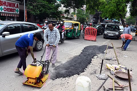 PWD workers fix a pothole on a road during the 24-hour pothole repair drive, at CR Park, in New Delhi,
