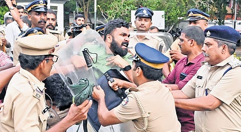 Police prevent SFI state secretary P S Sanjeev from entering the Kerala University campus during the protest on Wednesday