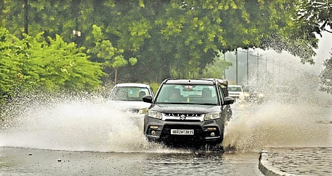 Commuters drive through the waterlogged road at Rajmahal Square, as heavy rain lashes Bhubaneswar