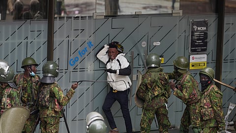 Police surround a demonstrator protesting on the one-year anniversary of deadly anti-tax demonstrations in Nairobi, Kenya, Wednesday, June 25, 20125