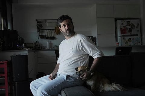 Liran Berman, brother of twins, Ziv and Gali Berman, who were abducted from their home in Kibbutz Kfar Aza on Oct 7, 2023, and held in the Gaza Strip, poses for a portrait at home with his family dog, Barbie, in Or Akiva, Israel, Wednesday, June 25, 2025.