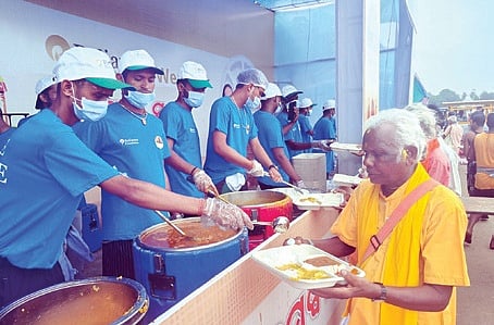 Volunteers of Reliance Foundation serve food to devotees on the eve of Rath Yatra, in Puri.
