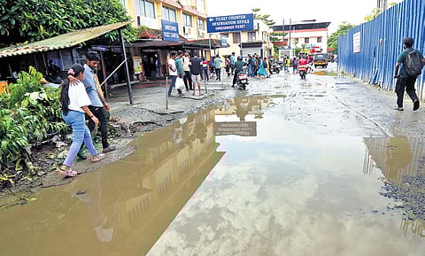 Commuters walk through the waterlogged section near the ticket-cum-reservation counter at the main entrance to the South railway station on Saturday
