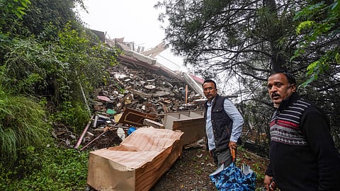 Shimla: Two men stand near the debris after a multi-storey building collapsed following heavy rainfall, at Bhatta Kufar, in Shimla, Monday, June 30, 2025.