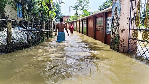 People move on road flooded by water from swollen Subarnarekha river, in Balasore district, Odisha, Monday, June 30, 2025.
