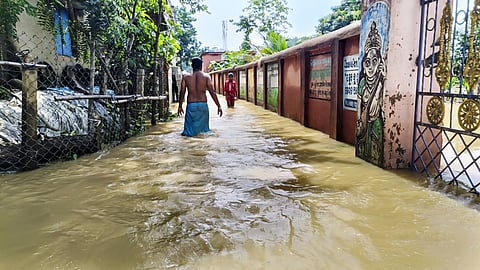 People move on road flooded by water from swollen Subarnarekha river, in Balasore district, Odisha