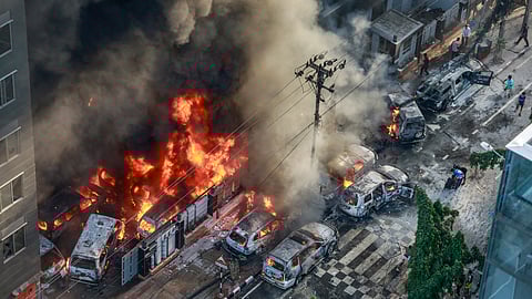 Smoke rises from the burning vehicles after protesters set them on fire near the Disaster Management Directorate office, during the ongoing anti-quota protest in Dhaka on July 18, 2024.