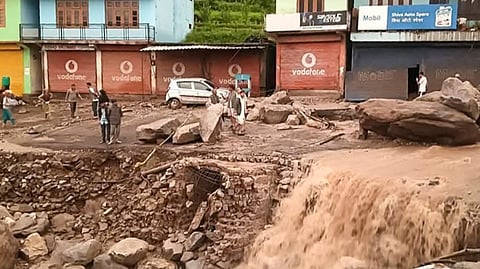 People stand near silt and debris after cloudburst-triggered flash floods at Karsog, in Mandi district, Tuesday, July 1, 2025.