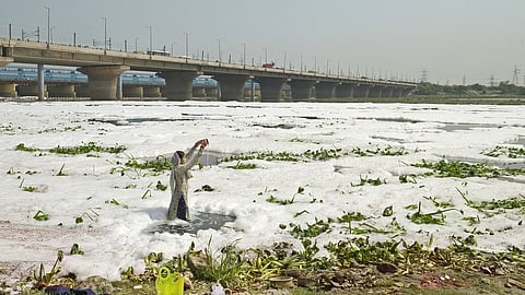 A woman performs puja in the toxic waters of the Yamuna River at Kalandi Kunj