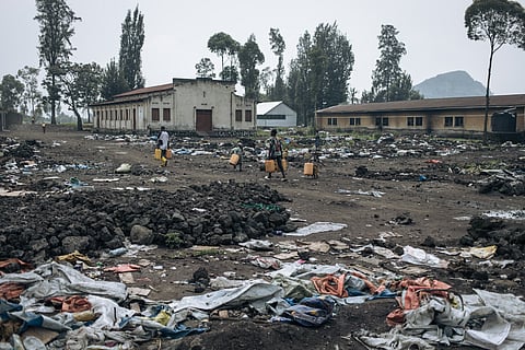 War-displaced people carry water as the camps empty of their population in Goma on February 2, 2025.