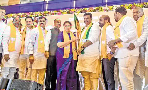 Outgoing State BJP chief D Purandeswari hands over the party flag to the newly elected president PVN Madhav in Vijayawada on Tuesday